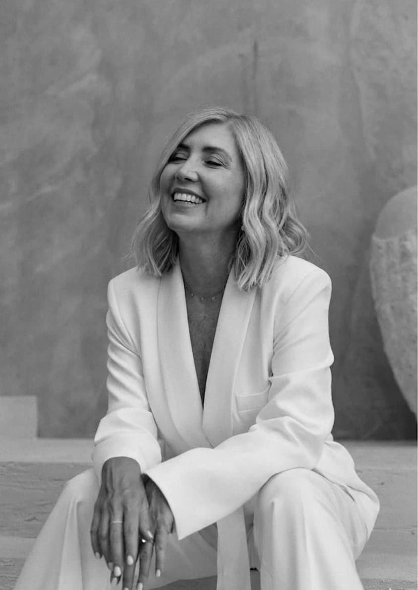 Alis sonriendo, sentada con un traje blanco